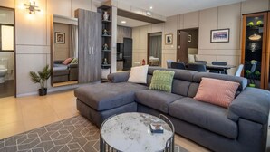 Ein modernes Wohnzimmer mit einer grauen Eckcouch, einem runden Couchtisch und einem Essbereich mit Tisch und Stühlen.