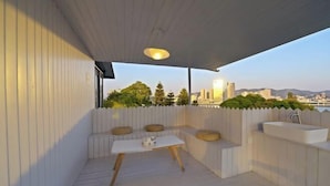 Un espacio al aire libre cubierto con mesas y bancos, un lavamanos y vistas de la ciudad.