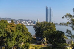 Un paisaje urbano costero con rascacielos modernos, una masa de agua y abundante vegetación.