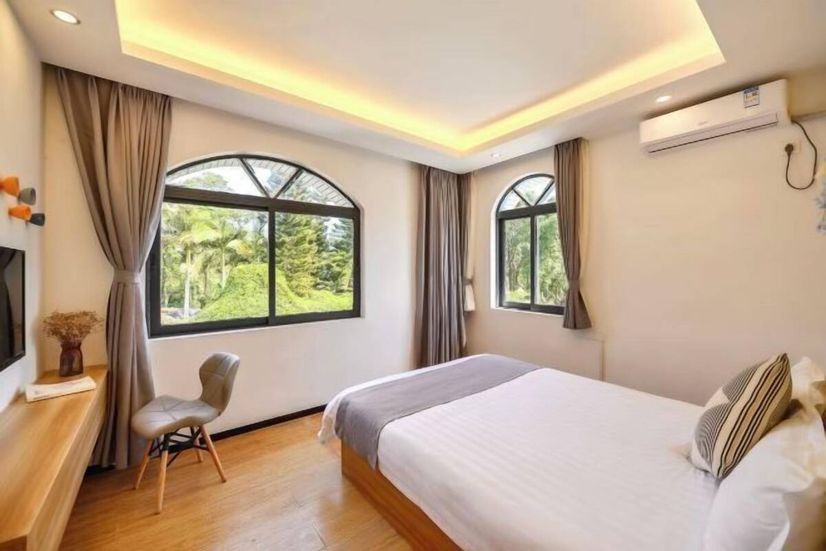 A modern bedroom with a bed, two windows, a chair, and an air conditioning unit.