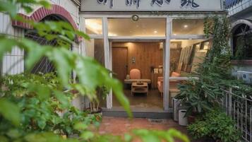 A traditional Japanese-style entrance with a wooden door and a small seating area inside.