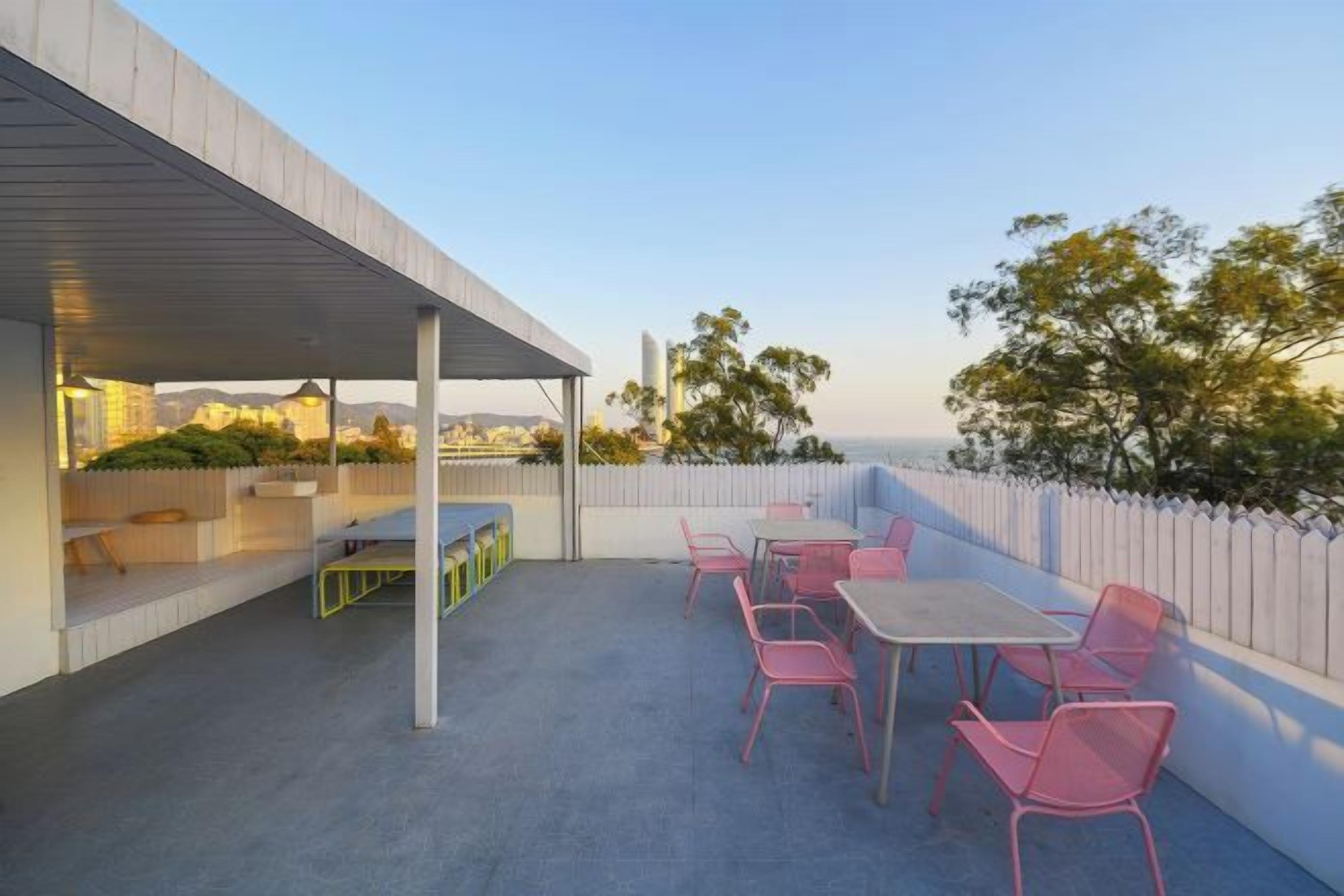 An outdoor patio with a table and chairs, a covered seating area, and a view of the cityscape.