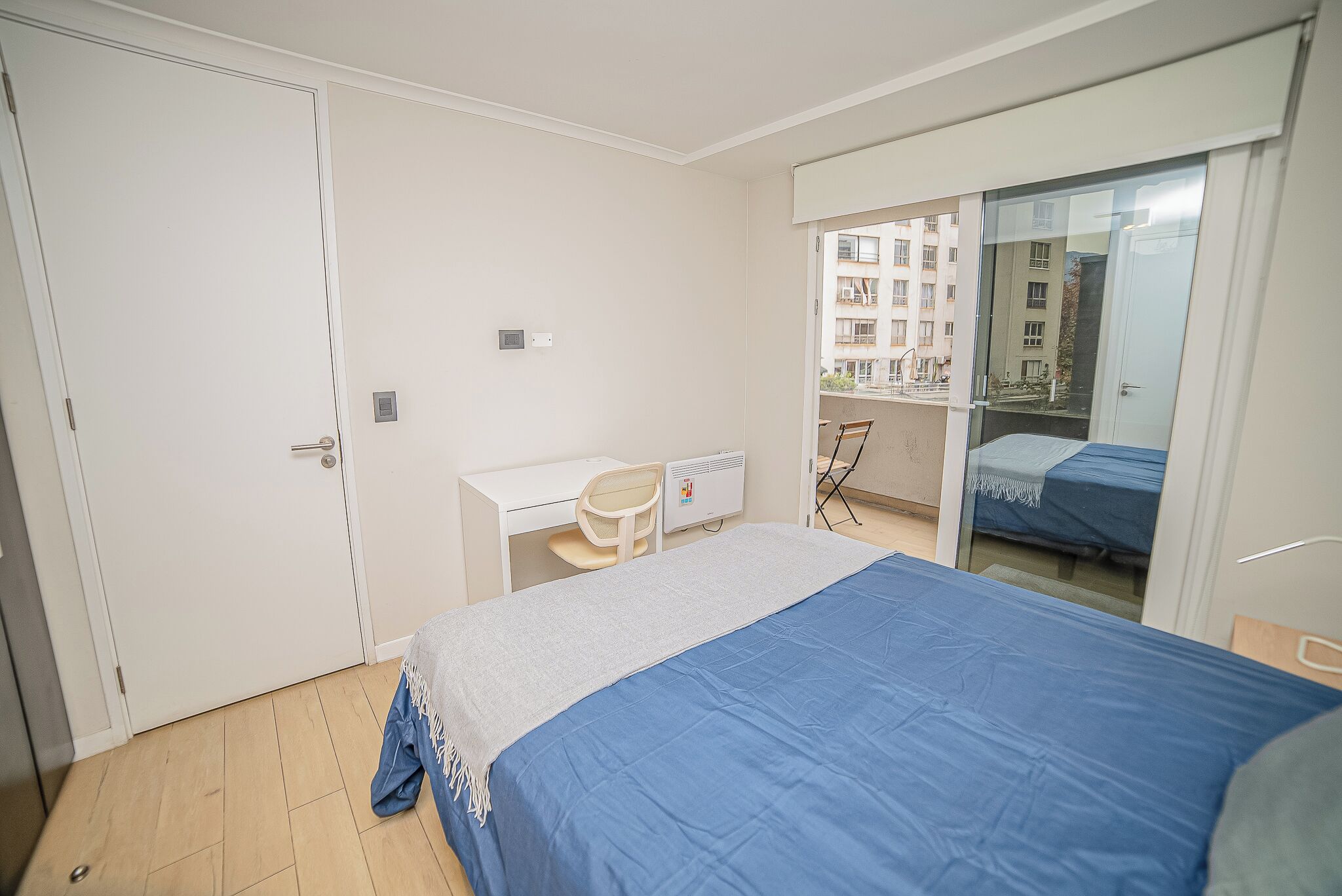 A bedroom with a bed, a desk, and a chair.