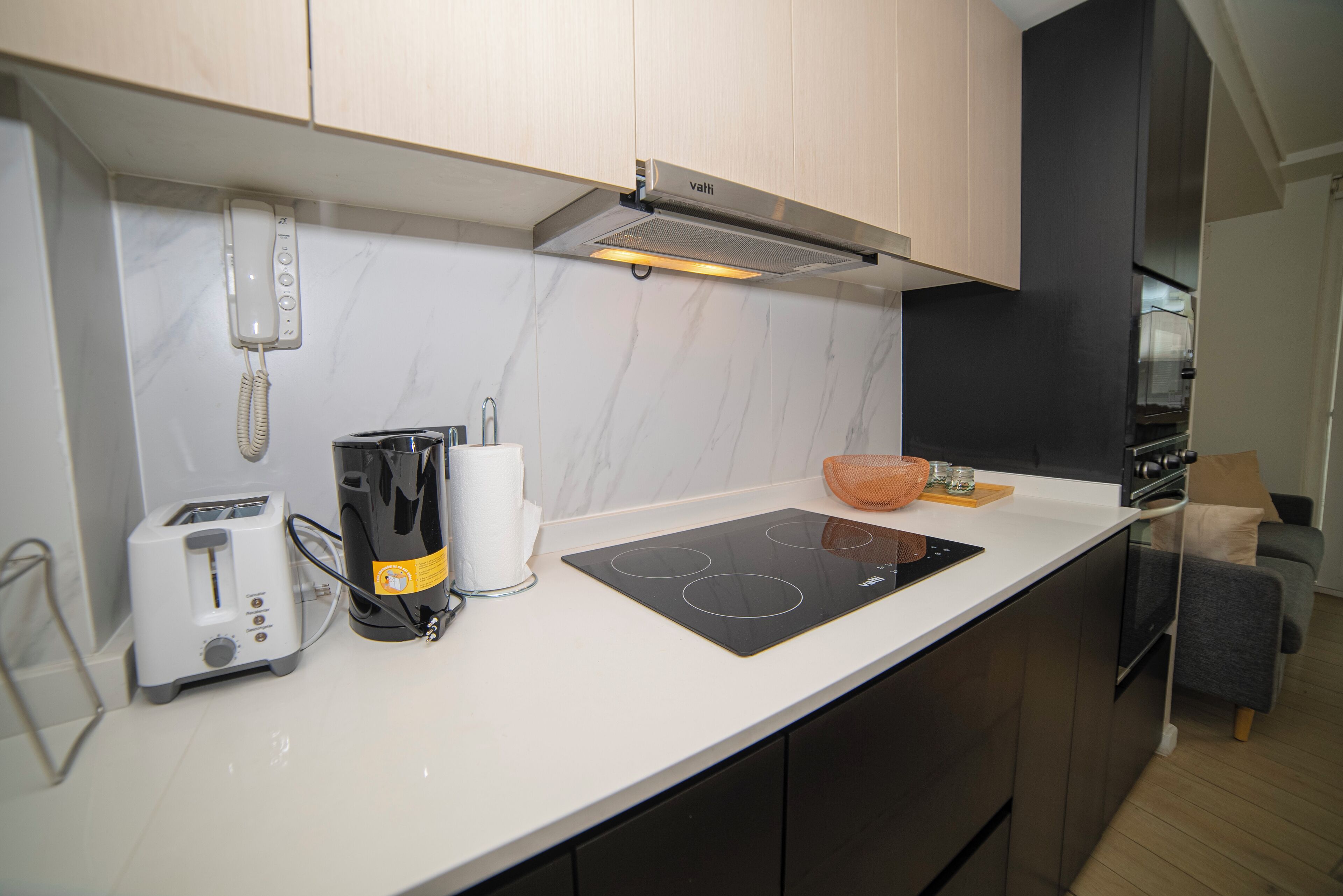 A compact kitchen with a built-in toaster, a coffee maker, and a modern induction cooktop.