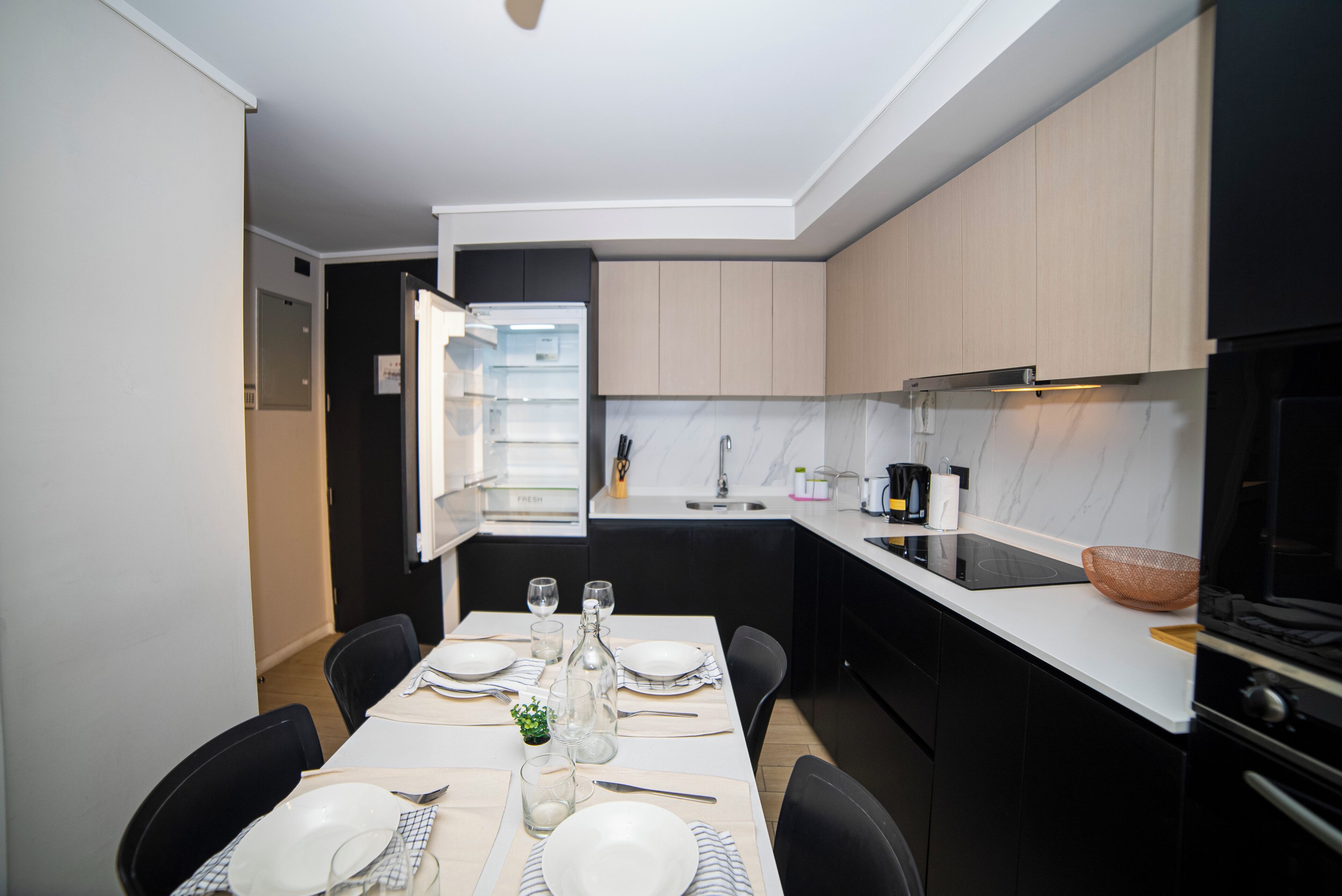 Una cucina moderna con zona pranzo, dotata di forno a incasso, lavello e piano di lavoro con macchina da caffè.