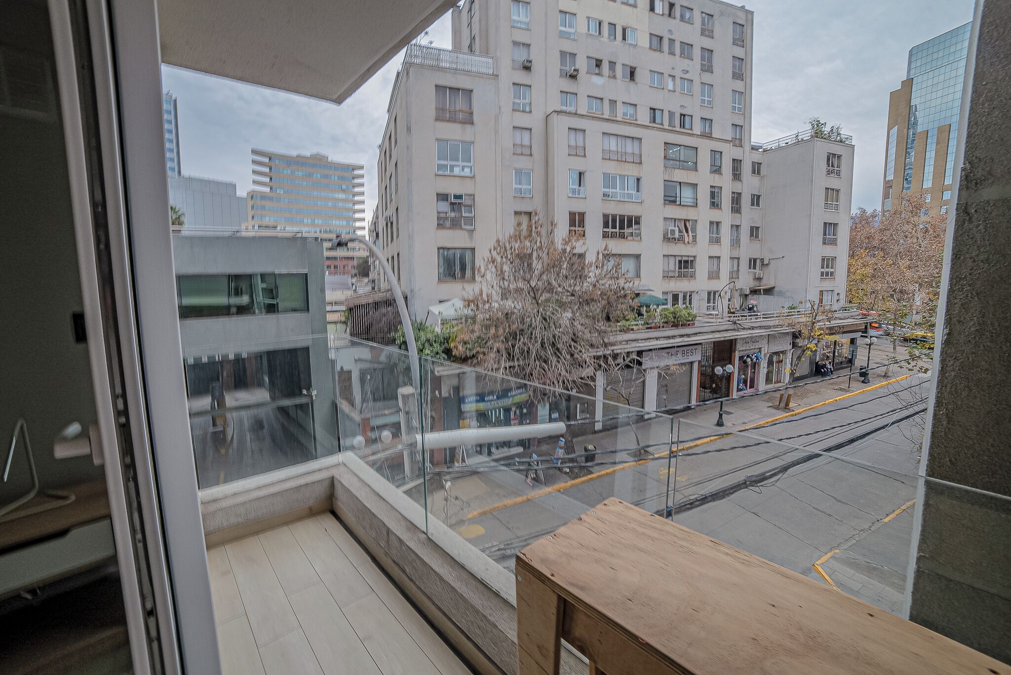 A balcony with a view of a cityscape, including a multi-story building and a tram line.