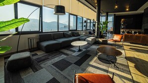 Ein modernes Wohnzimmer mit einer Eckcouch, einem runden Couchtisch und einem großen Fenster mit Blick auf die Stadt.