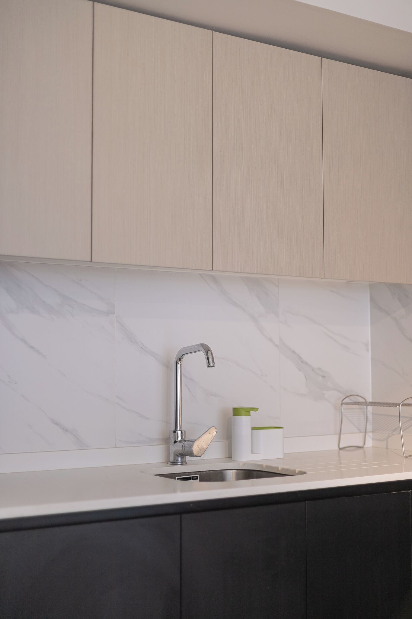 Uma cozinha moderna com painel de parede de mármore, pia de aço inoxidável e armários minimalistas.