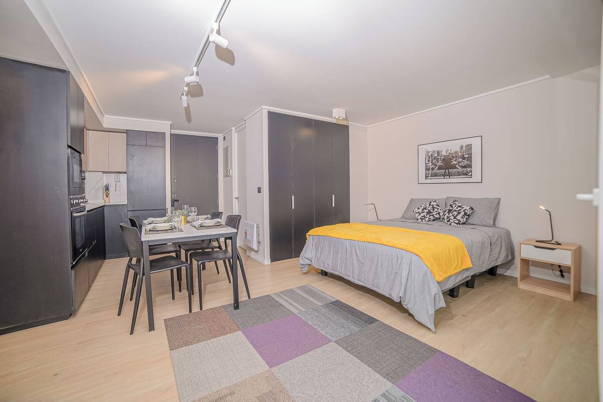Une chambre à coucher moderne avec un lit, une table de chevet et un bureau avec des chaises.
