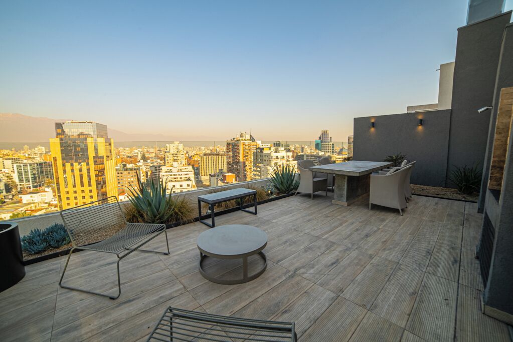 Une terrasse sur le toit offrant une vue sur le paysage urbain, avec une table et des chaises, un banc et des plantes en pot.