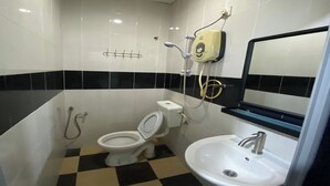 Une petite salle de bain avec des toilettes, un lavabo et une douche.