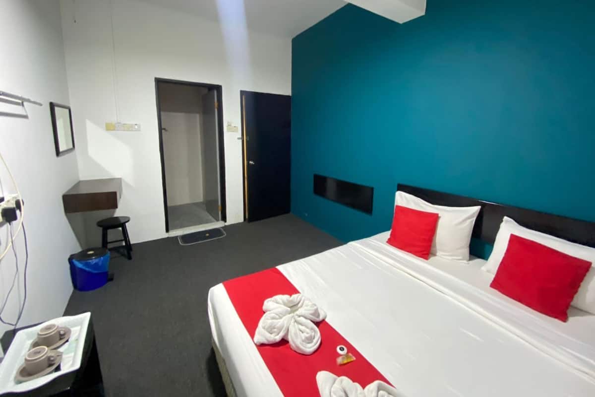 Una habitación de hotel con cama, espejo, lavamanos y un cubo de basura azul.