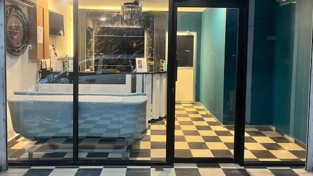 Un hall d’hôtel avec un sol à carreaux, un comptoir d’accueil et un lustre.