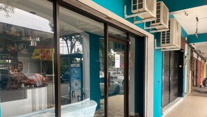 L’entrée d’un hôtel avec un sol à carreaux, une porte en verre et des unités de climatisation fixées au mur.