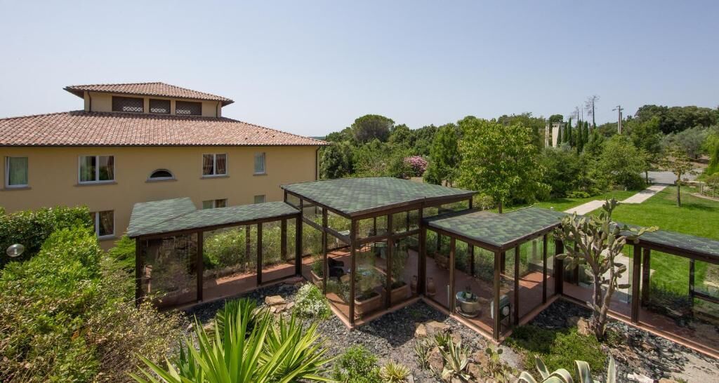A villa with a large garden, a glass-enclosed patio, and a traditional tiled roof.