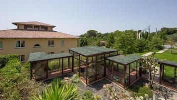 A villa with a large garden, a glass-enclosed patio, and a traditional tiled roof.