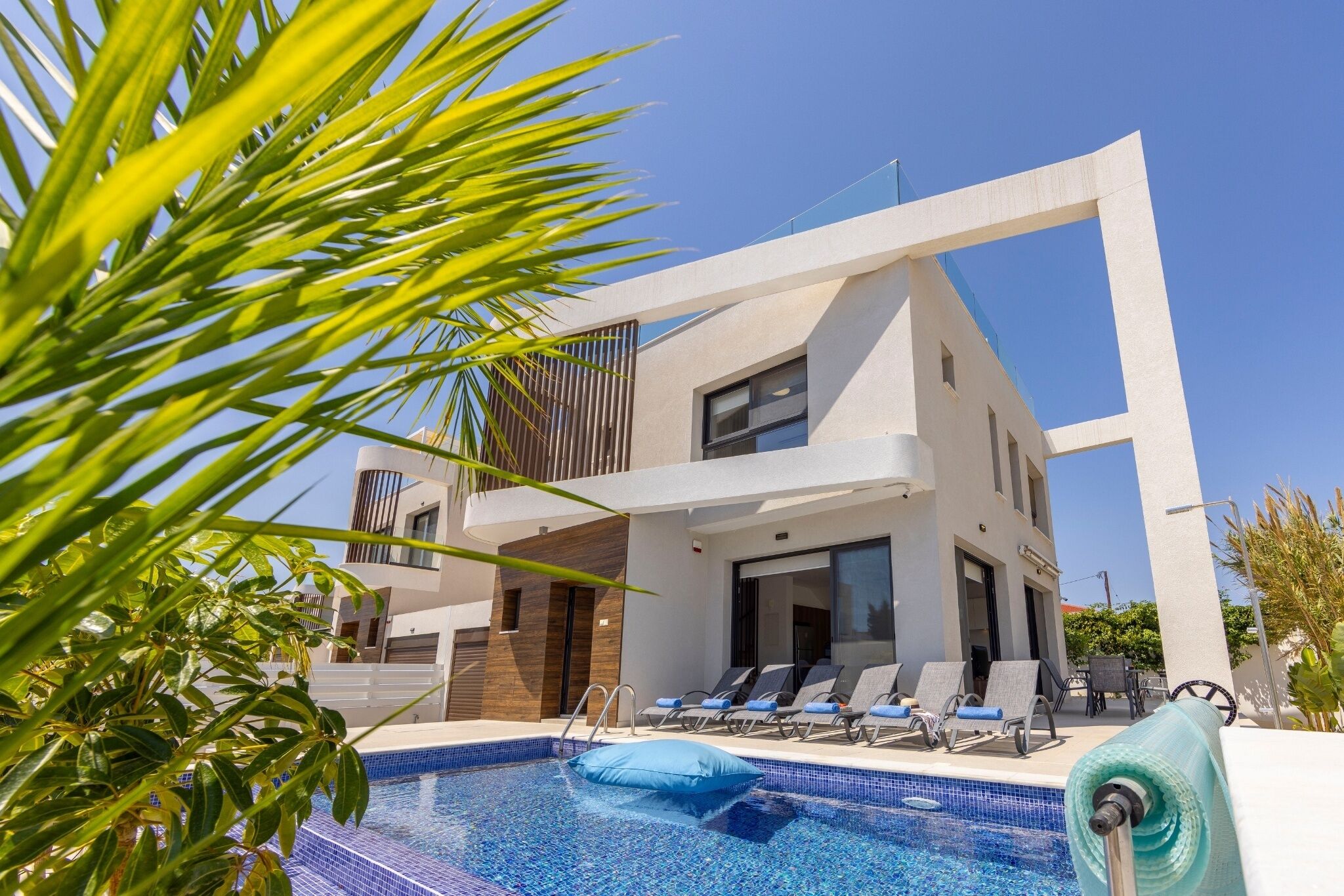 A modern building with a pool area, including lounge chairs and a clear blue pool.
