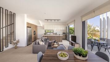 A modern open-plan living area with a kitchen, dining table, and seating.