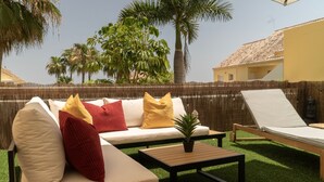 Un espacio al aire libre con sofás, cojines, una mesa y una silla de descanso.