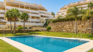 Una piscina rectangular con muro de piedra y palmeras en un entorno de resort.