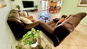 A living room with a brown leather sofa, a glass coffee table, and a TV. - Ref 902. Stunning villa own pool, games room. Near Disney (Four Corners)