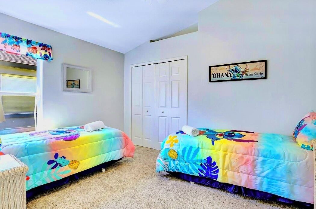 Een slaapkamer met twee bedden, een witte deur en een bord aan de muur.