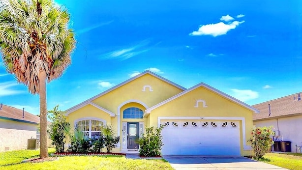 A two-story house with a garage, a well-maintained lawn, and a palm tree.