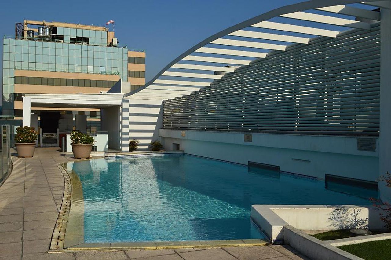 A modern building with a pool, large windows, and a unique curved roof structure.