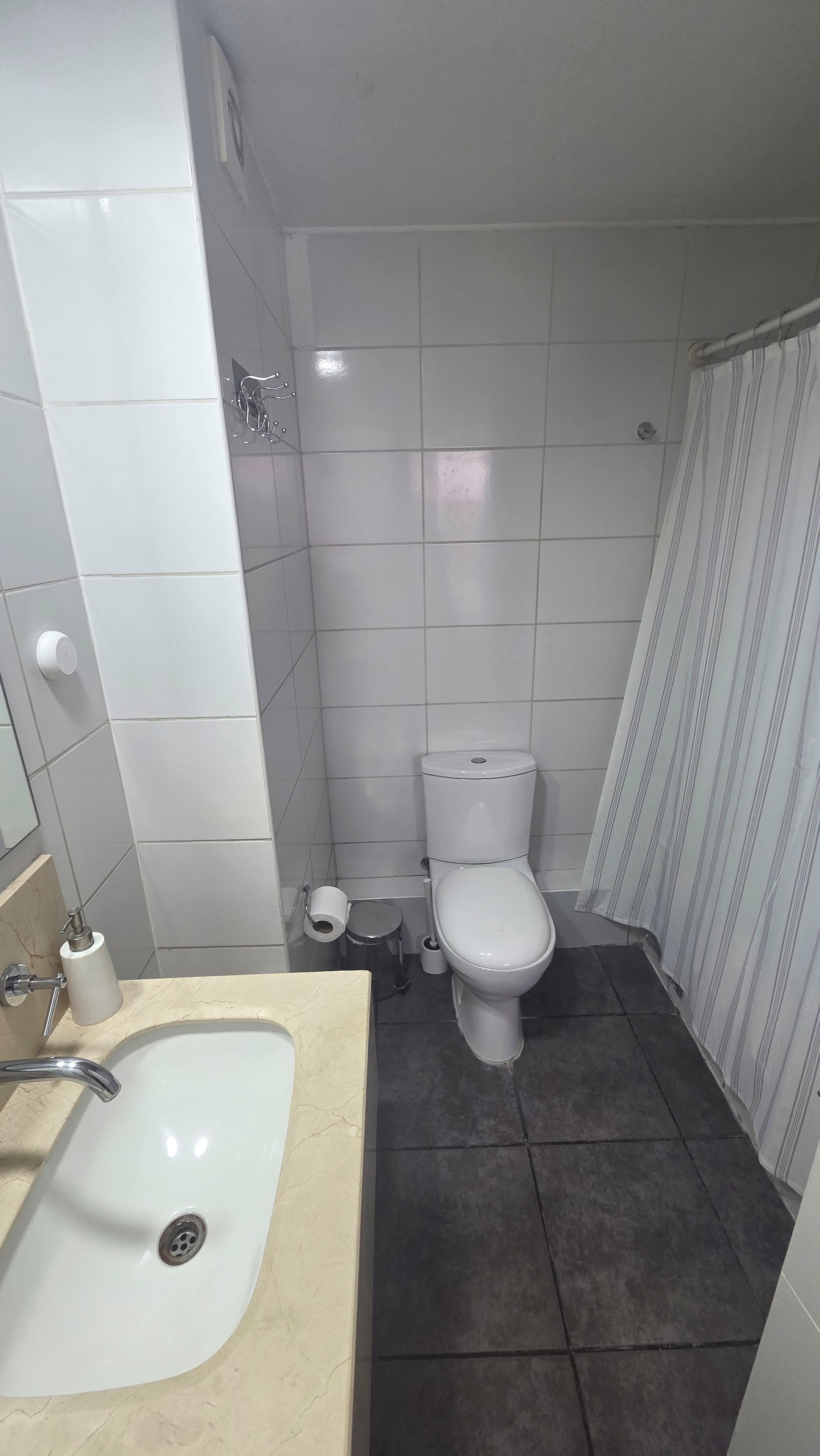 A bathroom with a white sink, toilet, and shower curtain.