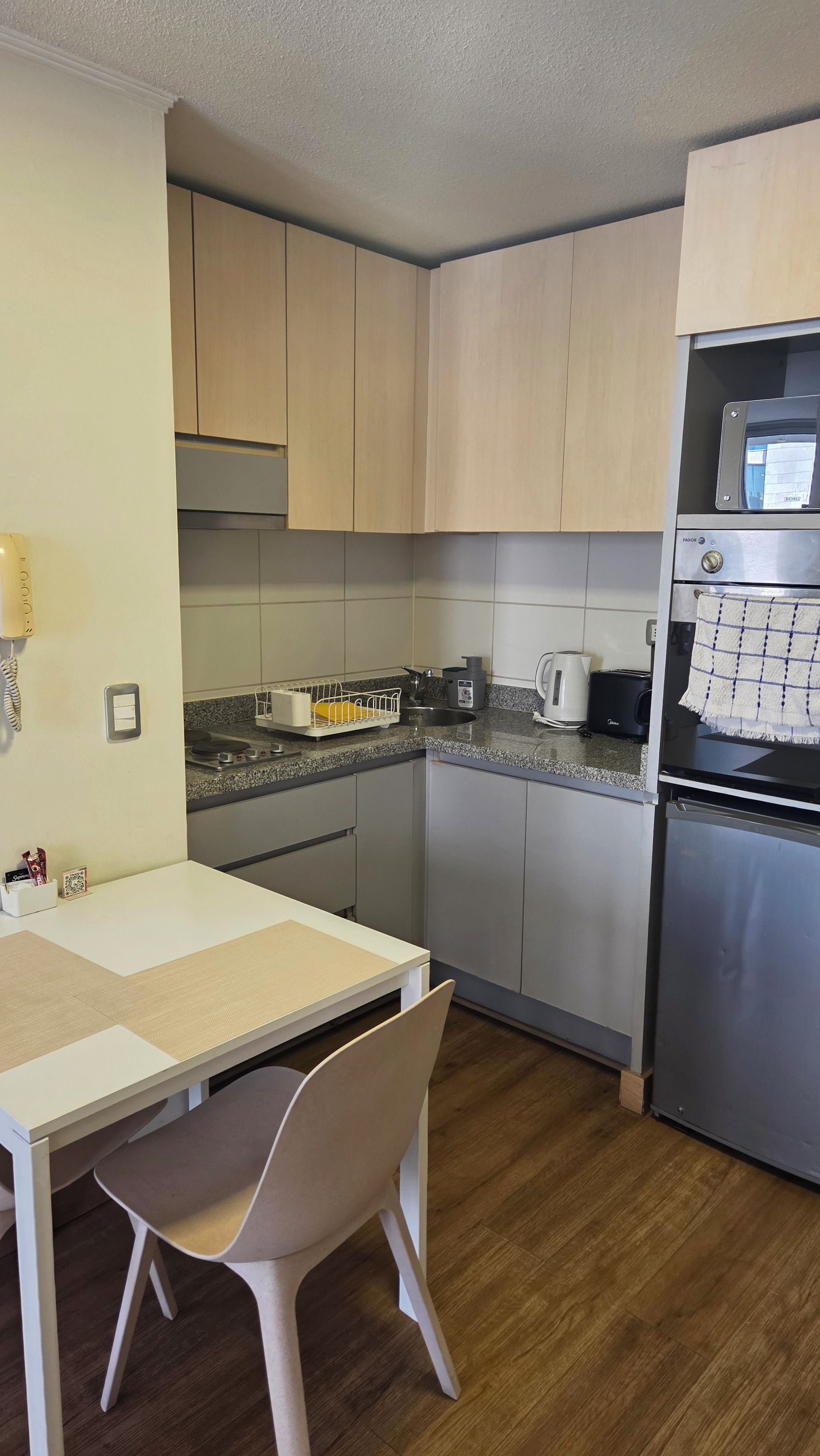 Une cuisine de taille réduite comprenant une table à manger, des chaises, un four à micro-ondes et un réfrigérateur.