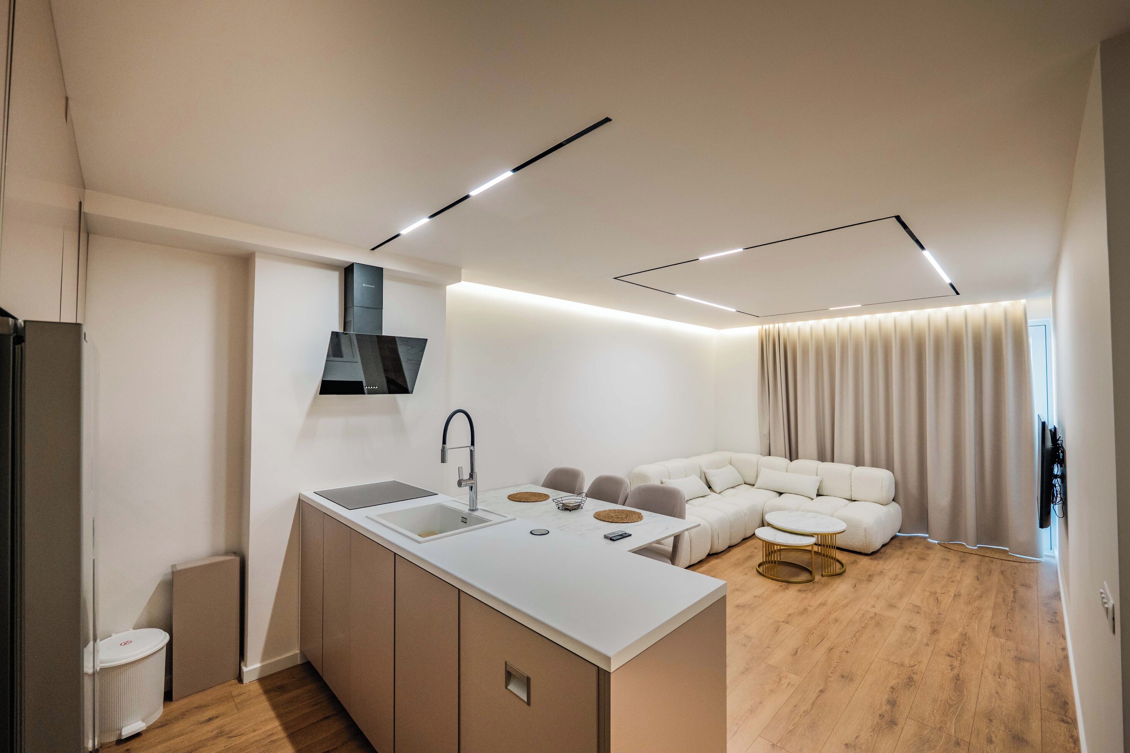 A modern kitchen with a built-in island, a dining area with a round table, and a living area with a sofa and a coffee table.