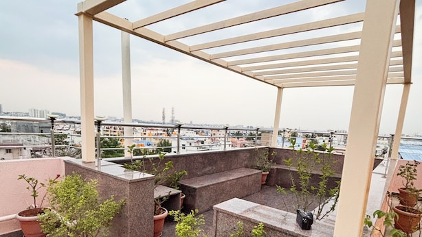 A rooftop terrace with a pergola, potted plants, and a view of the cityscape. - Visla Stay - Premium Serviced Apartment  (Bengaluru)