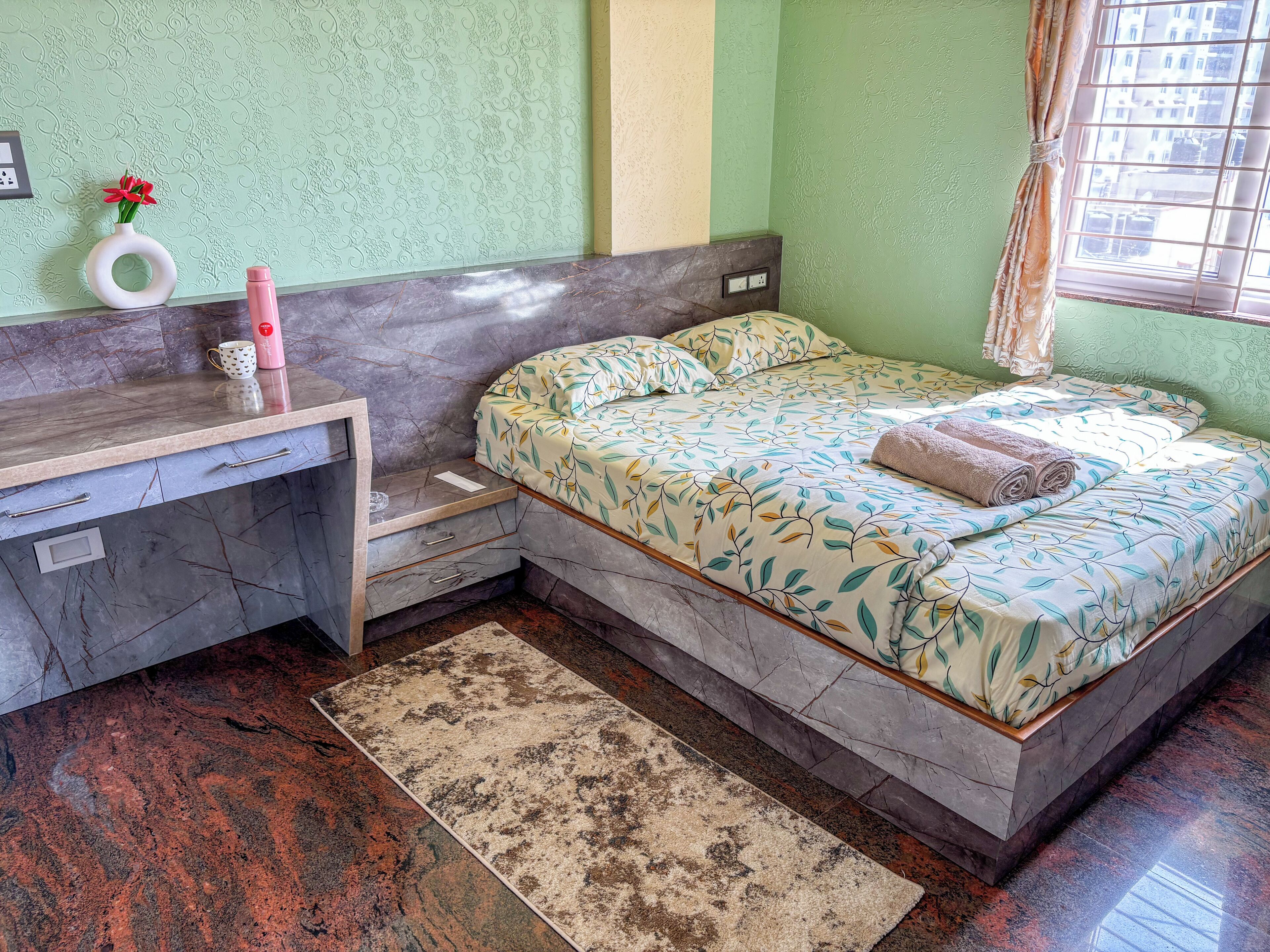 Un dormitorio con cama, mesita de noche y un pequeño escritorio con silla.