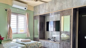 A modern hotel room with a bed, a desk, a flat-screen TV, and a wardrobe. - Visla Stay - Premium Serviced Apartment  (Bengaluru)