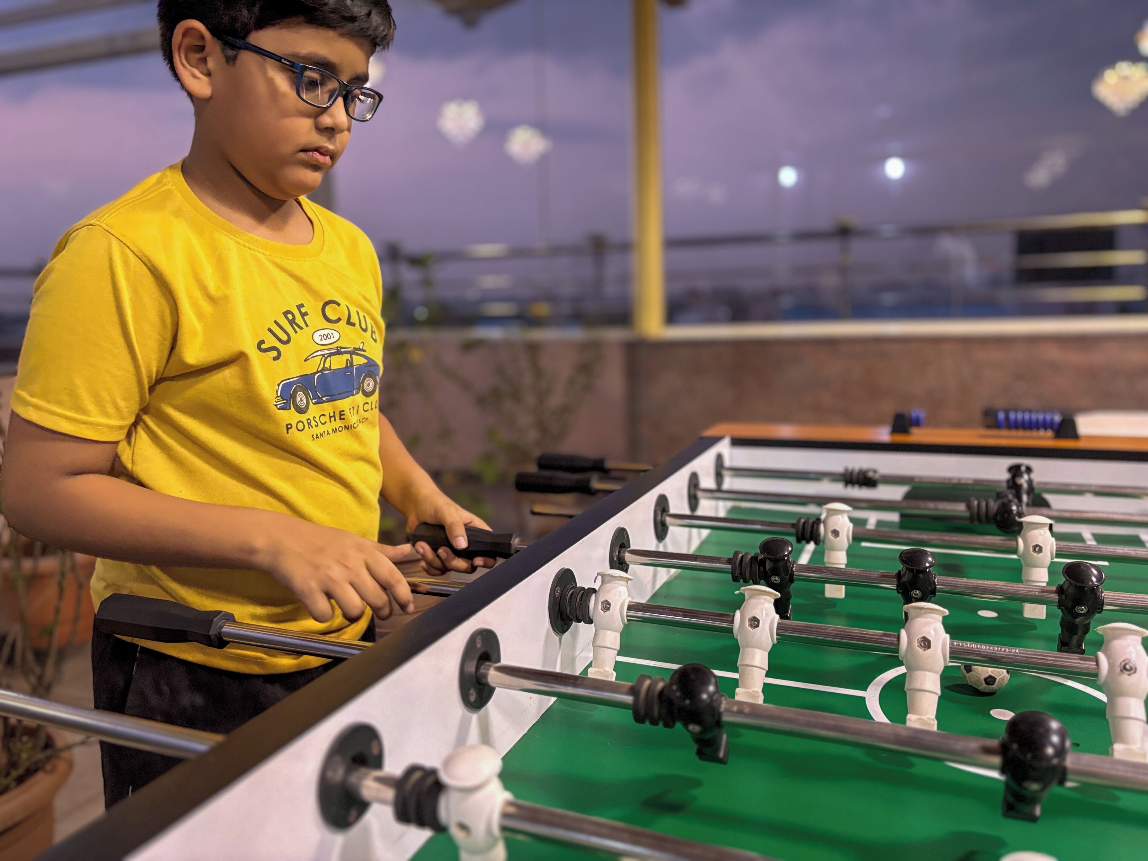 Una persona juega al fútbol de mesa en un espacio interior con un campo verde.
