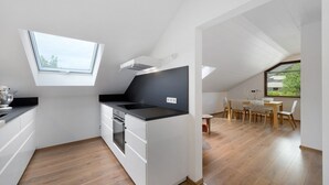 A modern kitchen with a skylight, a dining area with a table and chairs, and a view of greenery outside.