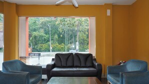 Una habitación con un sofá de cuero negro, dos sillones azules y una mesa de centro de madera.
