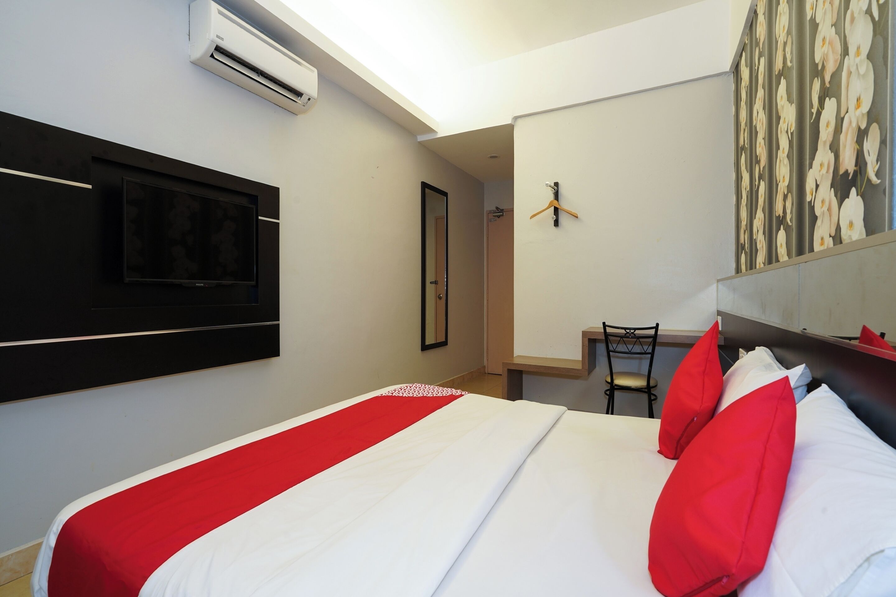 Una camera d'albergo con un letto, una TV a schermo piatto montata a parete, una poltrona e una scrivania.