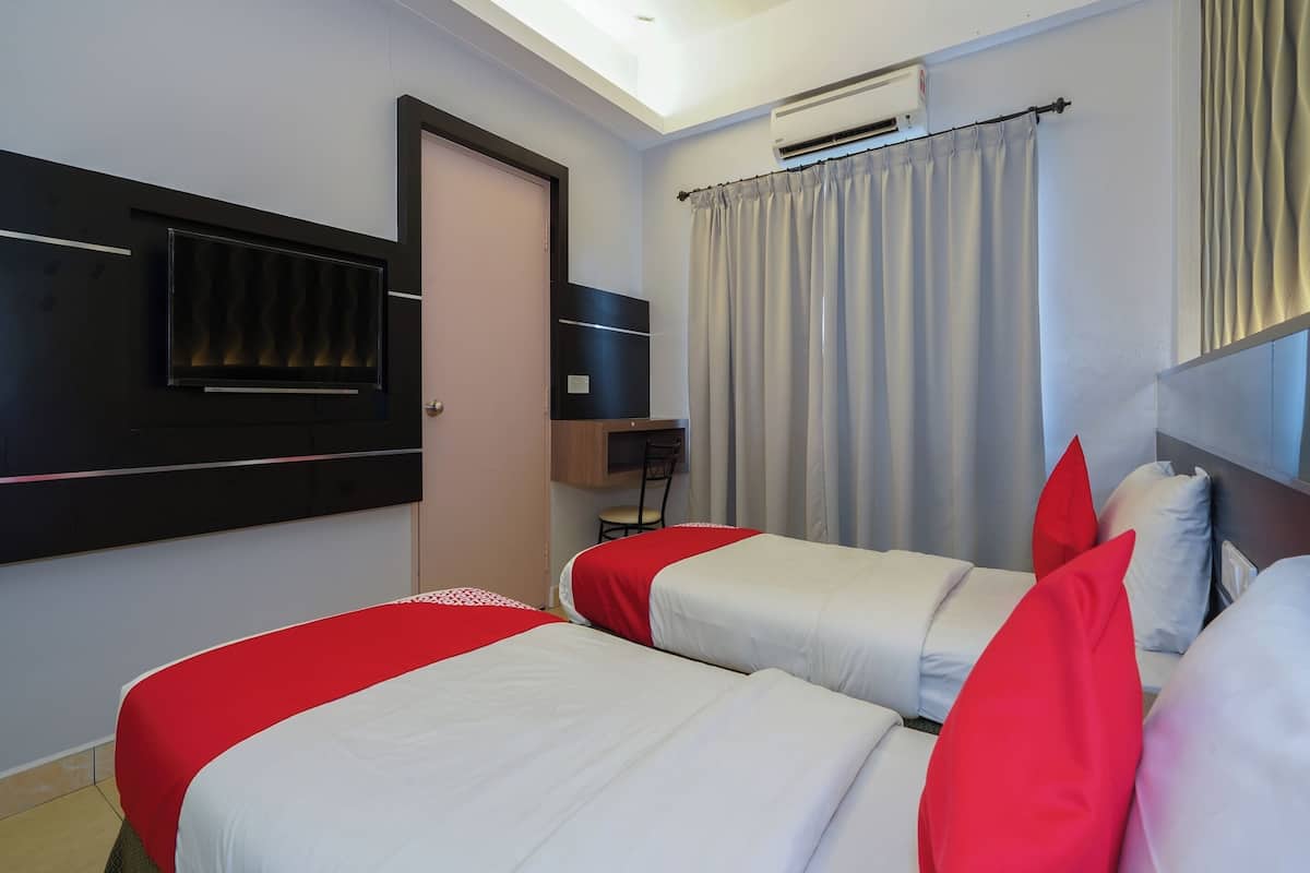A hotel room with two beds, a TV, an air conditioner, and a curtain.