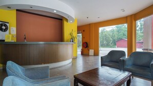 Un área de recepción con un mostrador curvo, sillas tapizadas en azul y una mesa de centro de madera.