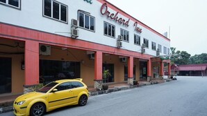 Un hotel llamado 'Orchard Inn' con un auto amarillo estacionado frente a él.