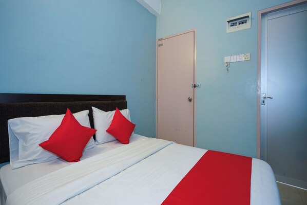 A neatly made bed with white and red bedding, a closed door, and a wall-mounted electrical outlet. - Dancenter Near Shell Jalan Iskandar Shah, Orchard (Lumut)