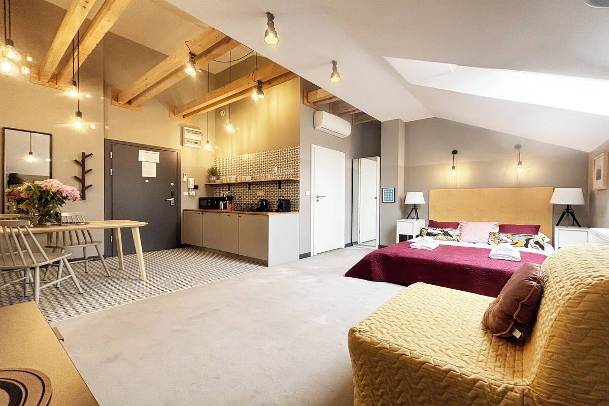 Una habitación de hotel moderna con una cama grande, un comedor y una cocina.