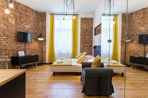 A modern room with a brick wall, a bed with yellow curtains, a desk, and a chair. - 19Rooms (Kraków)