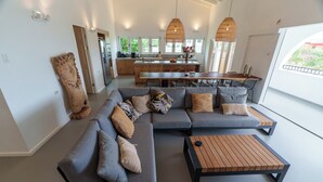 Een moderne woonkamer met een hoekbank, een houten salontafel en een eethoek met een groot schiereiland en stoelen.