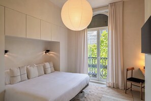 Une chambre moderne avec un grand lit, une vue sur un balcon et un luminaire suspendu.
