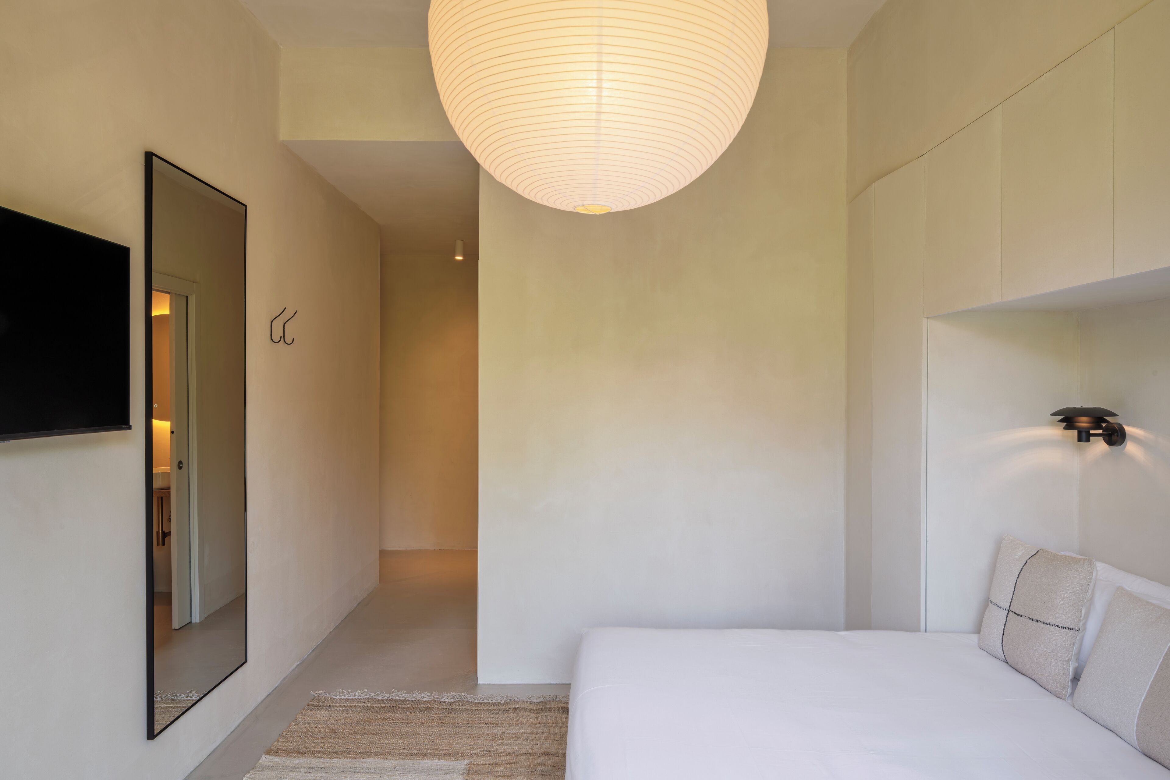 Una camera da letto moderna con un letto grande, una televisione a schermo piatto, uno specchio e un lampadario.