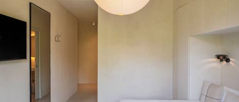 Una camera da letto moderna con un letto grande, una televisione a schermo piatto, uno specchio e un lampadario.