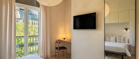 Una habitación de hotel con una cama, un escritorio con una silla, un televisor en la pared y un espejo grande.