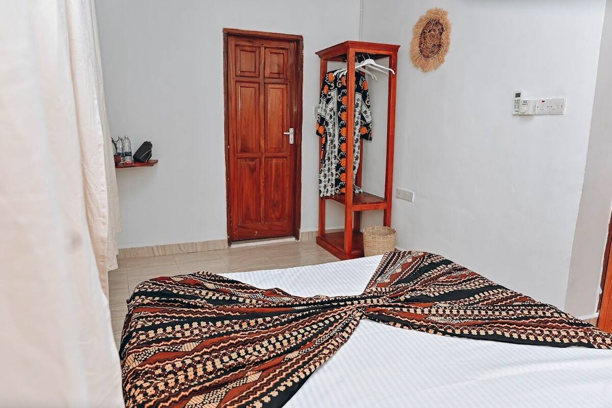 Un dormitorio con cama, armario, espejo y un calefactor en la pared.